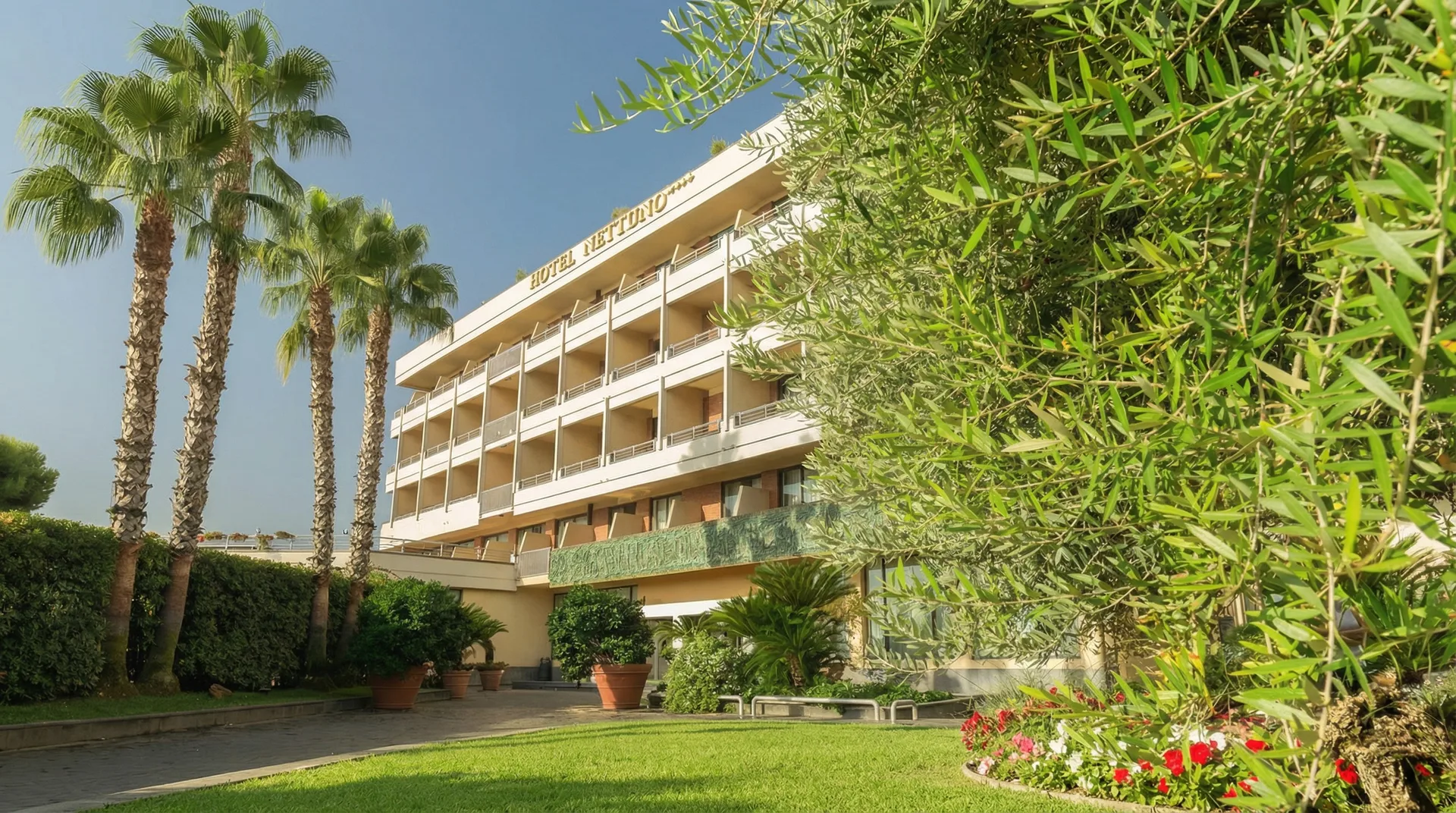 La facciata dell’Hotel Nettuno tra le palme del giardino, Catania